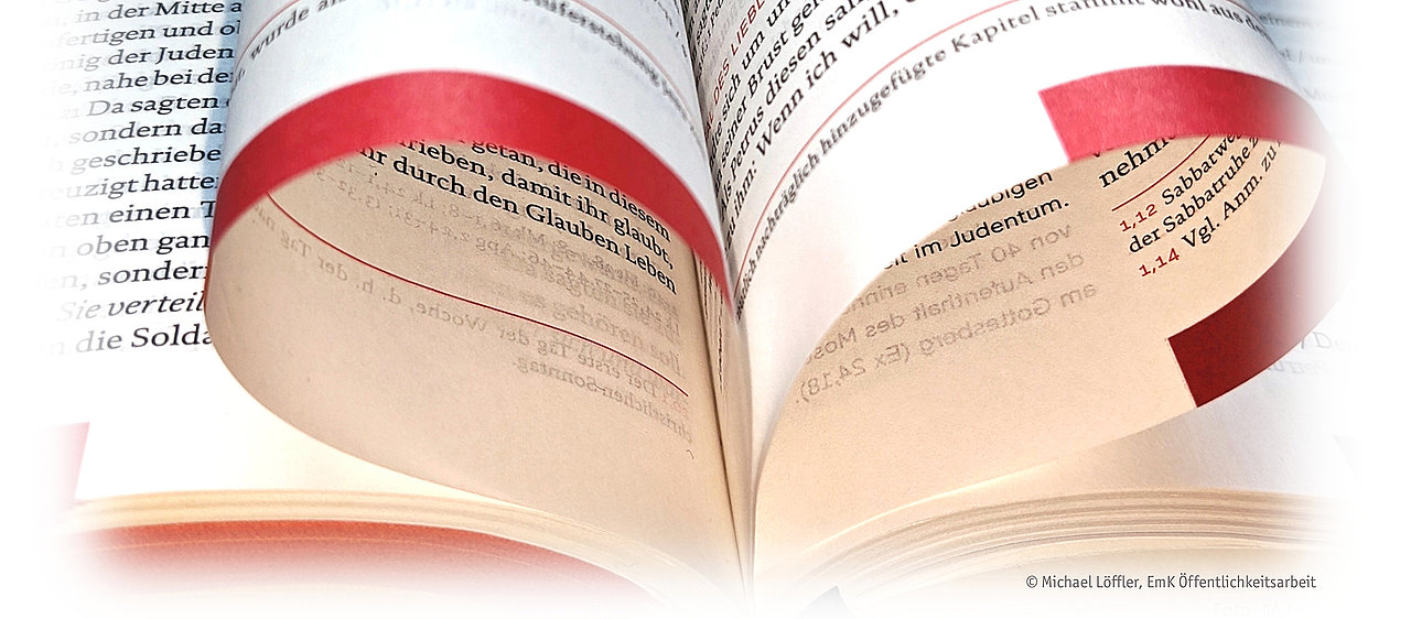 Aufgeschlagene Bibel mit gebogenen Seiten, die ein Herz formen.